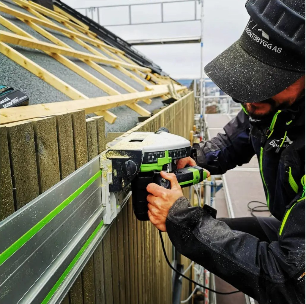 Håndverker fra Barentsbygg AS i arbeid på taket av et hus under oppføring